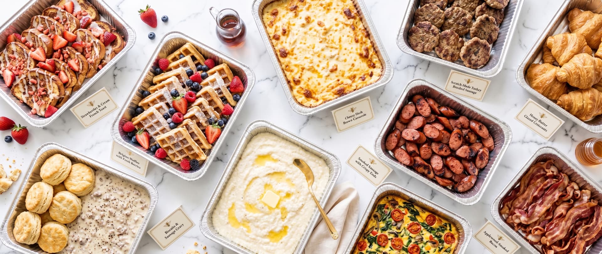 Labeled brunch catering spread with French toast, croissants, grits, biscuits and sausage gravy, hash brown casserole, and breakfast meats